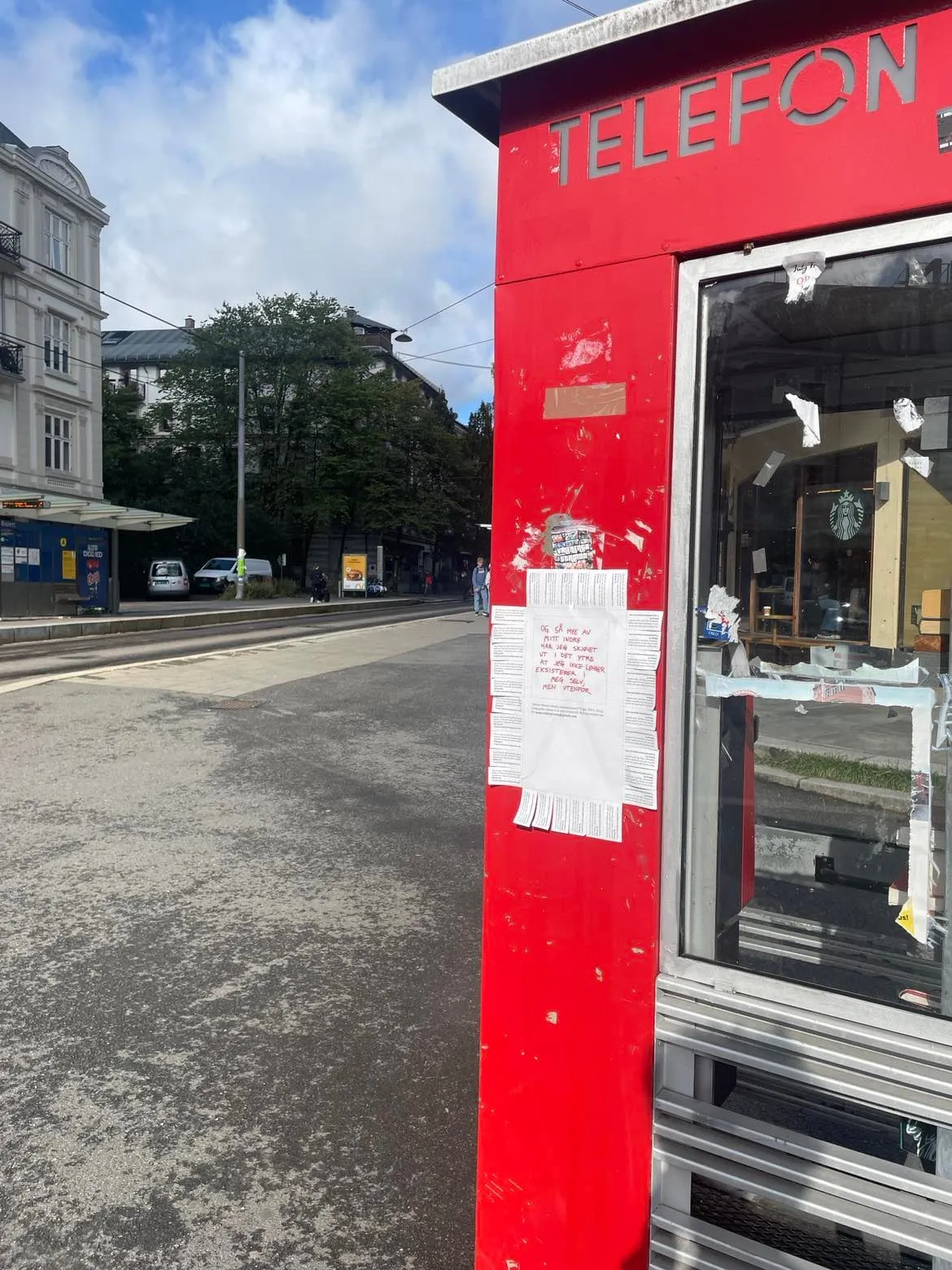 Red telephone kiosk with a Tekst1 call-for-contributions flyer taped to it on an Oslo street