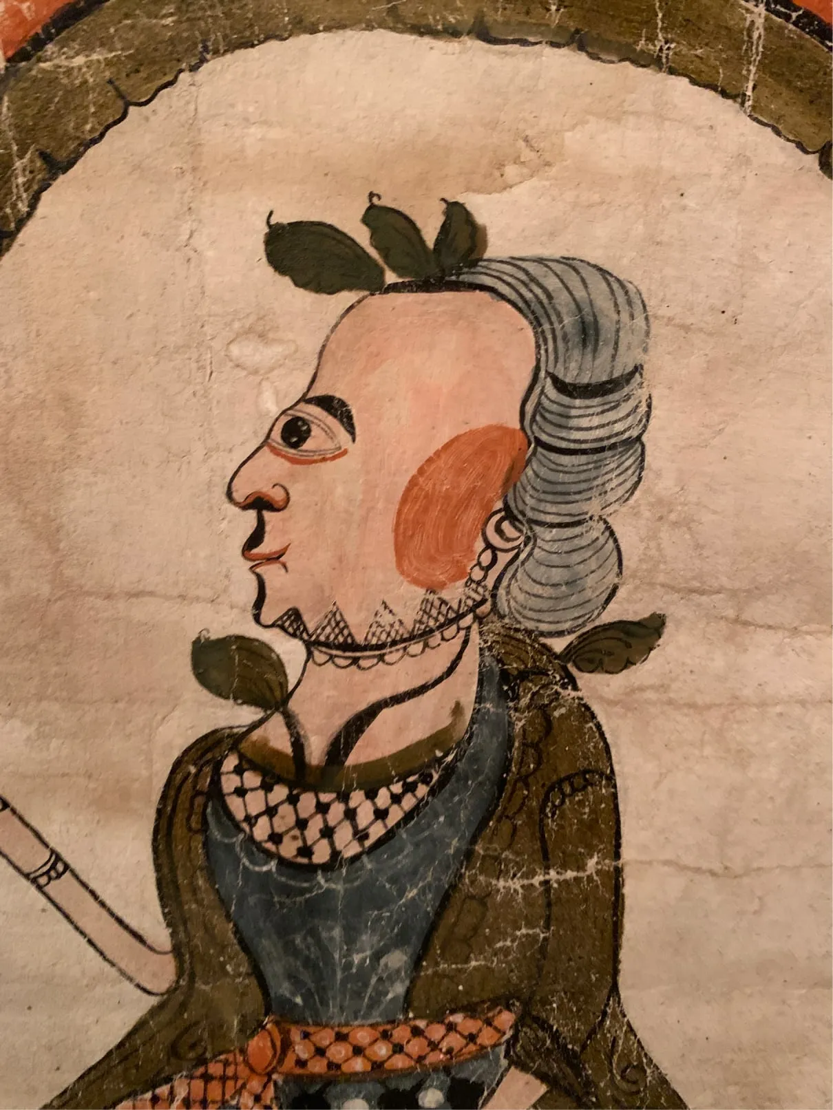 Detail of an old painted portrait of a man in profile with a grey wig and leaves in his hair