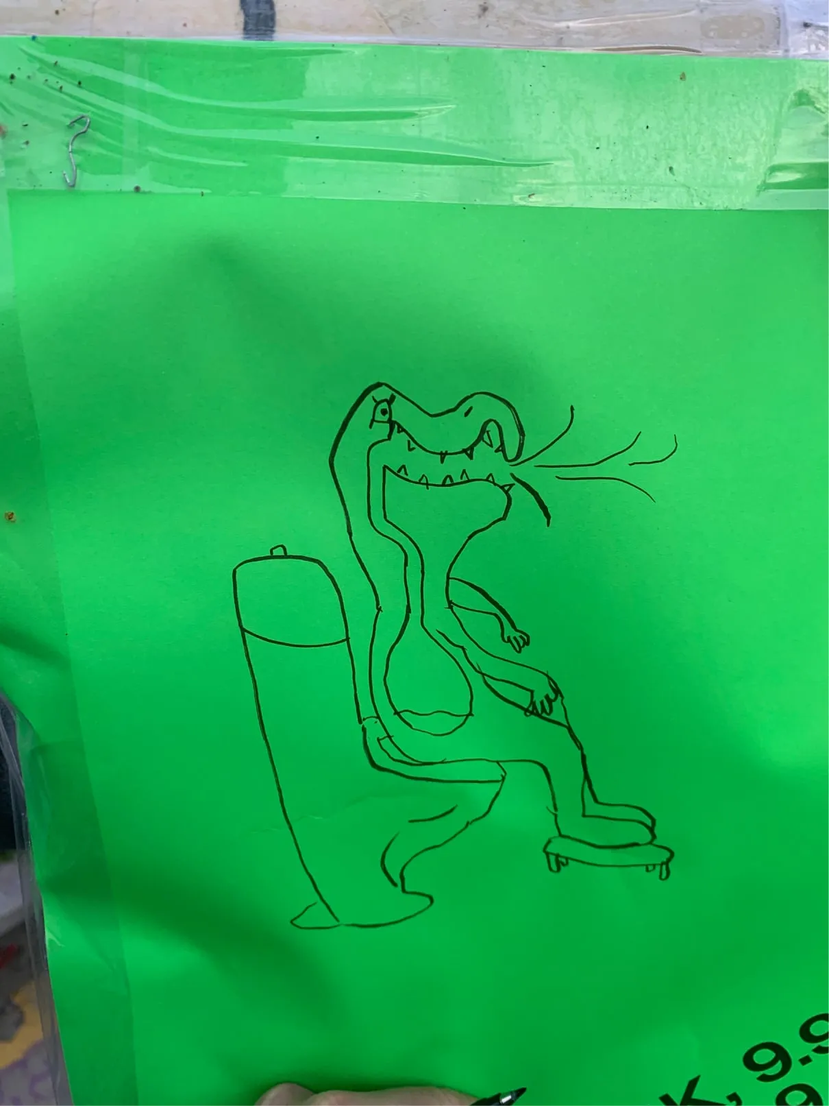 Hand-drawn crocodile sitting on a toilet on a bright green sheet of paper
