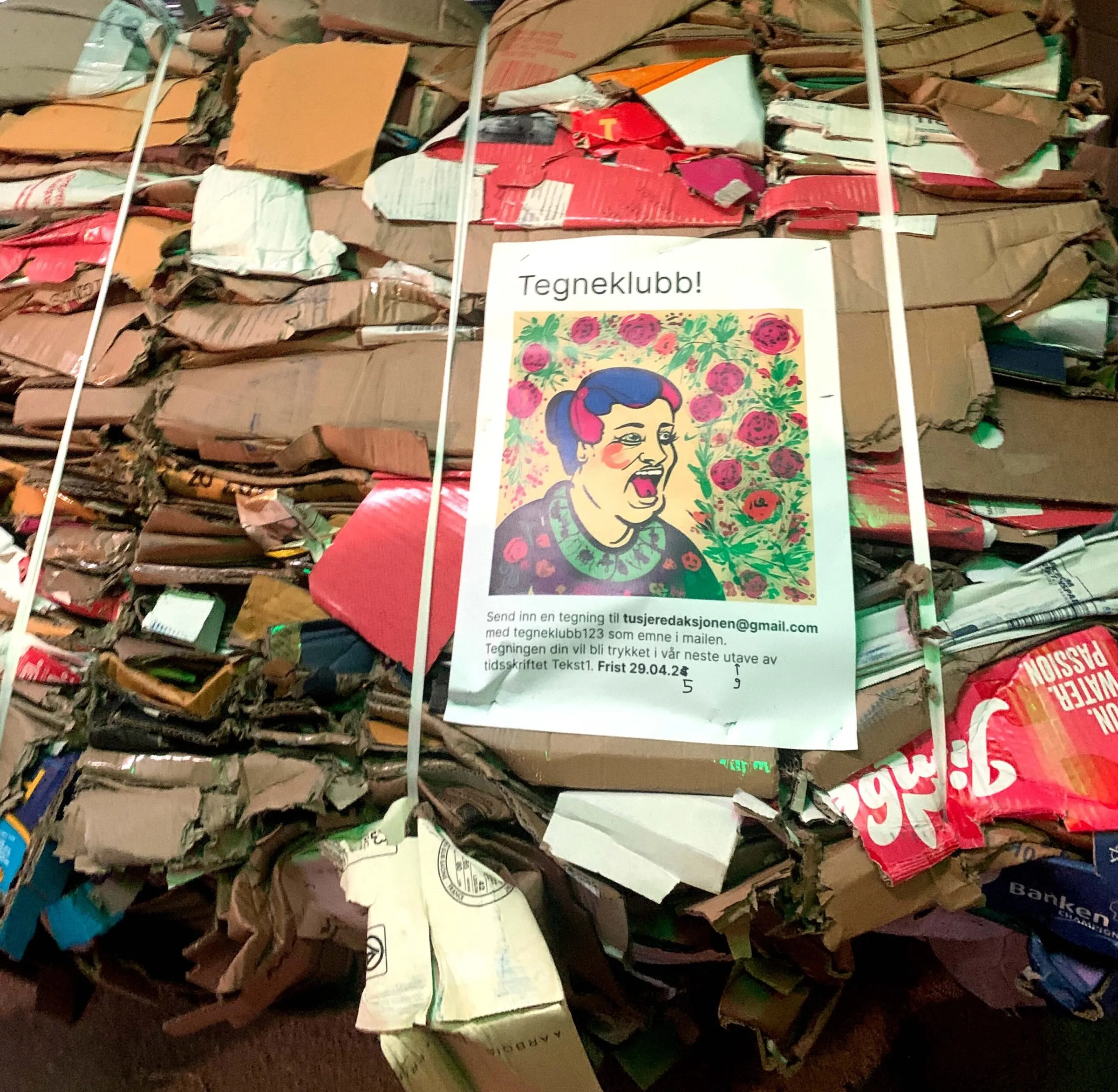 Tegneklubb flyer with a drawn smiling man among colourful objects, taped to a green fence at night